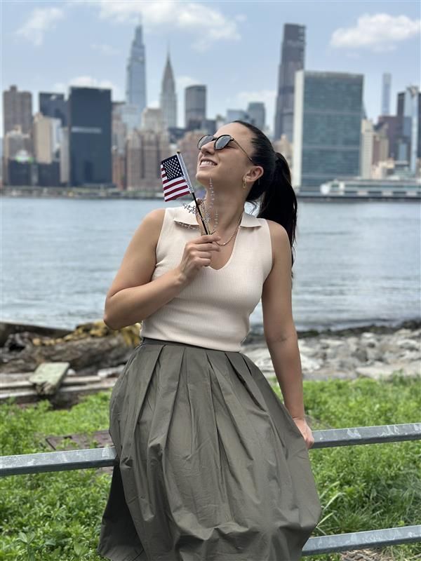 Ileana Pirozzi celebrating her American citizenship with a small flag and NYC skyline in background